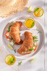 Tasty and fresh french croissant with camembert, prosciutto and tomatoes.