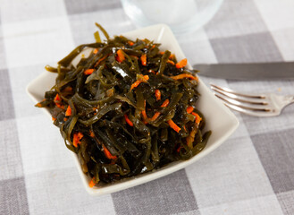 Japanese restaurant serves traditional vegetable appetizer, salad of fresh seaweed with grated carrot © JackF