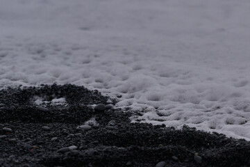 Sea foam on the shore of Reynisfjara black beach
