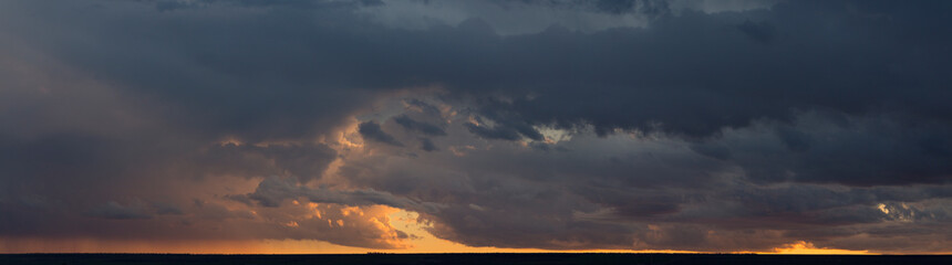Landscape at sunset. A thunderstorm is approaching the village. Tragic gloomy sky. Panorama.