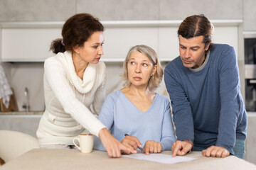 Man and woman help and advise elderly mother on how to make covenant while at home in kitchen