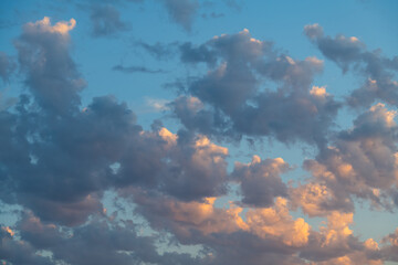 Photo of many voluminous clouds illuminated by the sun at sunset