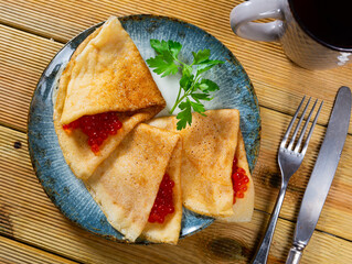 Ruddy soft pancakes with pile spoonful sturgeon roe. Dish is complemented by cup of tea
