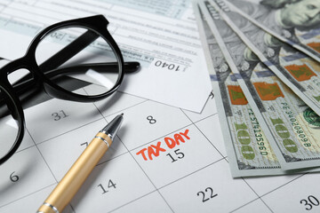 Calendar with date reminder about tax day, documents, money, pen and glasses, closeup