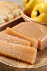 Tasty sweet quince paste, fresh fruits and bread on wooden table, closeup