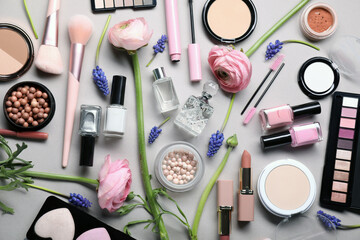 Flat lay composition with different makeup products and beautiful spring flowers on gray background