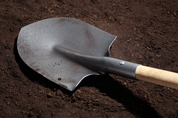 Metal shovel on fertile soil. Gardening tool