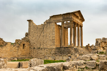 Monumental Capitol surrounded with stone ruins in historical Dougga in the Tebersouk Mountains, Tunisia