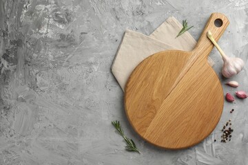 Cutting board, garlic, spices and rosemary on grey textured table, flat lay. Space for text