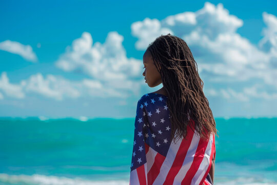 African American Woman Wrapped in American Flag Wrapped Contemplating Ocean Vistas