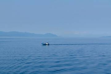 Panoramic view of the Alaskan mountain range on a summer day in August. A trawler is visible in the foreground.