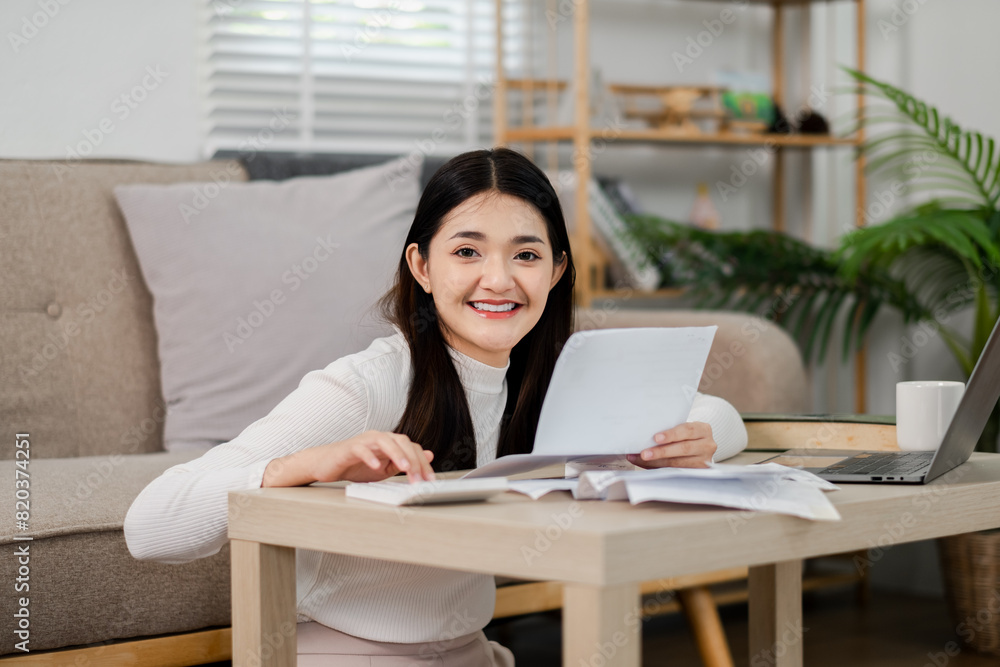 Poster a woman sitting at a table with a laptop and a stack of papers in front of her. she is smiling and s