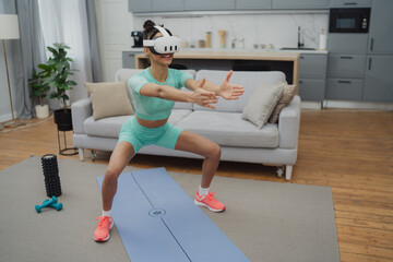 Obraz premium Beautiful young woman in sports clothing exercising at home