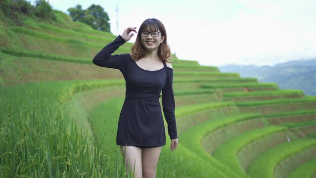 A farmer woman with fresh paddy rice terraces, green agricultural fields in countryside or rural area of Mu Cang Chai, mountain hills valley in Asia, Vietnam. Nature landscape. People lifestyle.