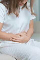 woman having abdomen ache due to Stomach pain, digestion with constipation or Diarrhea from food poisoning, female problem and Endometriosis, Hysterectomy, Stomachache and Menstrual on sofa at home