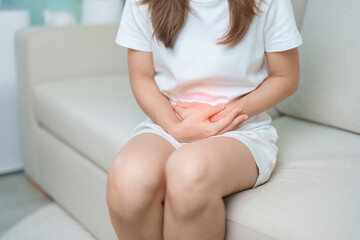 woman having abdomen ache due to Stomach pain, digestion with constipation or Diarrhea from food poisoning, female problem and Endometriosis, Hysterectomy, Stomachache and Menstrual on sofa at home