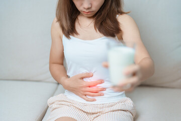 Lactose intolerance and Milk allergy concept. woman hold Milk glass and having abdominal cramps and...