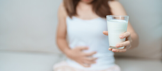 Lactose intolerance and Milk allergy concept. woman hold Milk glass and having abdominal cramps and...