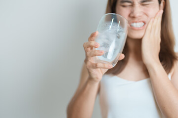 Teeth Sensitive to Cold concept. woman hold Ice Water glass and having toothache and pain after...