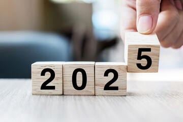 hand flipping block 2024 to 2025 text on table. Resolution, strategy, plan, goal, motivation,...
