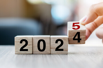 hand flipping block 2024 to 2025 text on table. Resolution, strategy, plan, goal, motivation,...