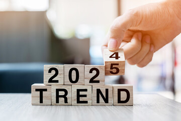 Businessman hand holding wooden cube with flip over block 2024 to 2025 Plans word on table background. Resolution, strategy, solution, goal, business and New Year holiday concepts