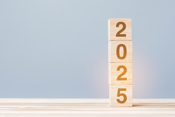 wooden cube block with 2025 text on table background. Resolution, plan, review, goal, start and New...