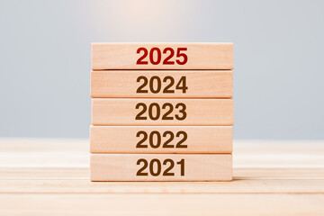 2025 block over 2024 and 2023 wooden building on table background. Business planning, Risk...