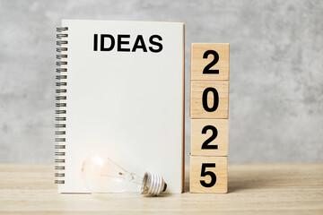 2025  text wood cube blocks and IDEAS word with lightbulb on table. New Year New Ideas, Creative,...