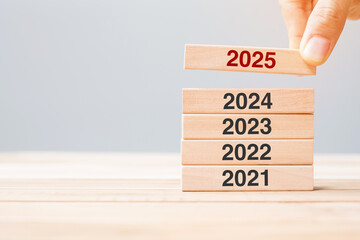 2025 block over 2024 and 2023 wooden building on table background. Business planning, Risk Management, Resolution, strategy, solution, goal, New Year New You and happy holiday concepts