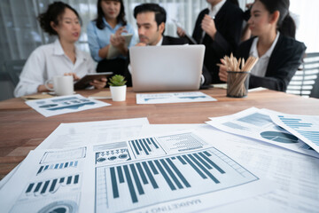 Piles of analyzed financial data dashboard on meeting table with background of business people...