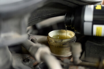 Auto mechanic adding brake fluid to the reservoirs.