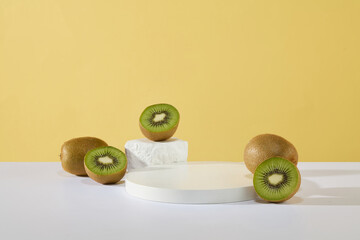 Blank podium in round shaped and a small block of stone arranged with some halves of kiwi. Minimal podium display for cosmetic product presentation. Yellow background