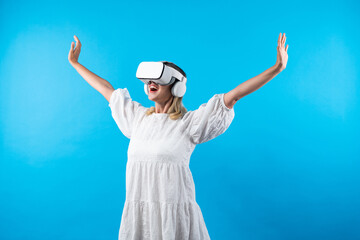 Caucasian girl enter metaverse while spread arms with relax at blue background. Excited woman enjoy...