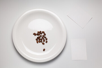 흰 배경에 원형 접시 위에 놓인 커피 원두와 메모지