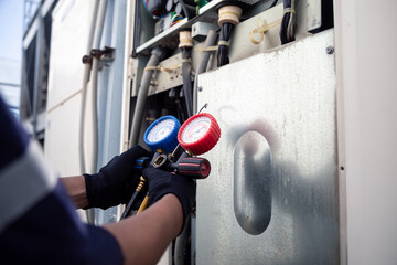 Air conditioning, HVAC service technician using gauges to check refrigerant and add refrigerant,Air...