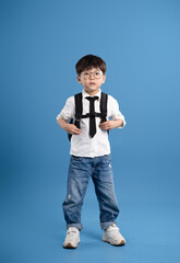 Full body image of Asian school boy posing on blue background