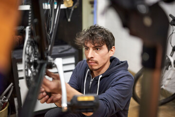 Portrait of an hispanic man focused assembling a bicycle in his bike shop as part of a maintenance...