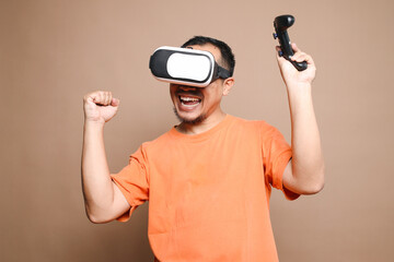 Excited man playing virtual games using VR glasses and joystick isolated on beige background