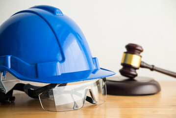 Hammer judge gavel with construction hat helmet, worker safety glasses on wooden table. Labour law...