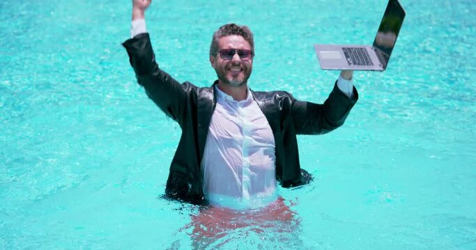 Business man in suit working on laptop in swimming pool. Travel tourism and business concept. Crazy male Business office employee using laptop in pool on summer day. Summer Business.