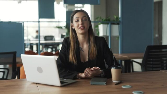 young, beautiful woman of Caucasian appearance talks while looking at the camera, blows a kiss, and makes a heart gesture