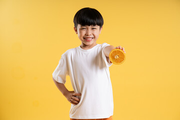 Portrait of adorable asian boy posing on yellow background