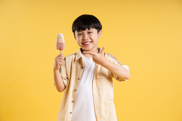 Portrait of adorable asian boy posing on yellow background © Q88