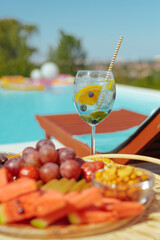 Fruit cocktail and a food tray by the pool.