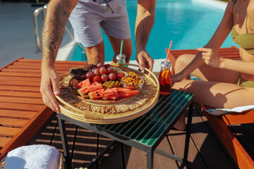 Tattooed man serving a tray of fresh fruits and drinks