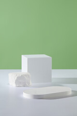 Several white podiums in geometric shapes are featured. Pastel green background. Product...