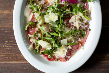 A top down view of a plate of steak carpaccio.