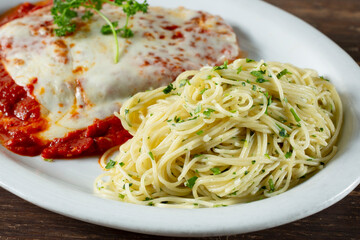 A view of a plate of angel hair pasta and chicken parmesan.