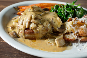 A view of an entree featuring a filet mignon topped with a mushroom bearnaise sauce.